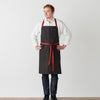 Chef Cross Back Apron Baker for Men Women Charcoal Black with Red Straps and Pockets Reluctant Trading Restaurant Quality Wholesale Pricing