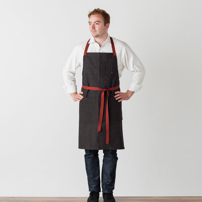 Chef Cross Back Apron Baker for Men Women Charcoal Black with Red Straps and Pockets Reluctant Trading Restaurant Quality Wholesale Pricing