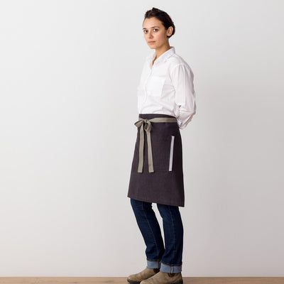 Bistro Apron on Model, Side View, Charcoal Black with Tan Straps, Half Apron, Reluctant Trading
